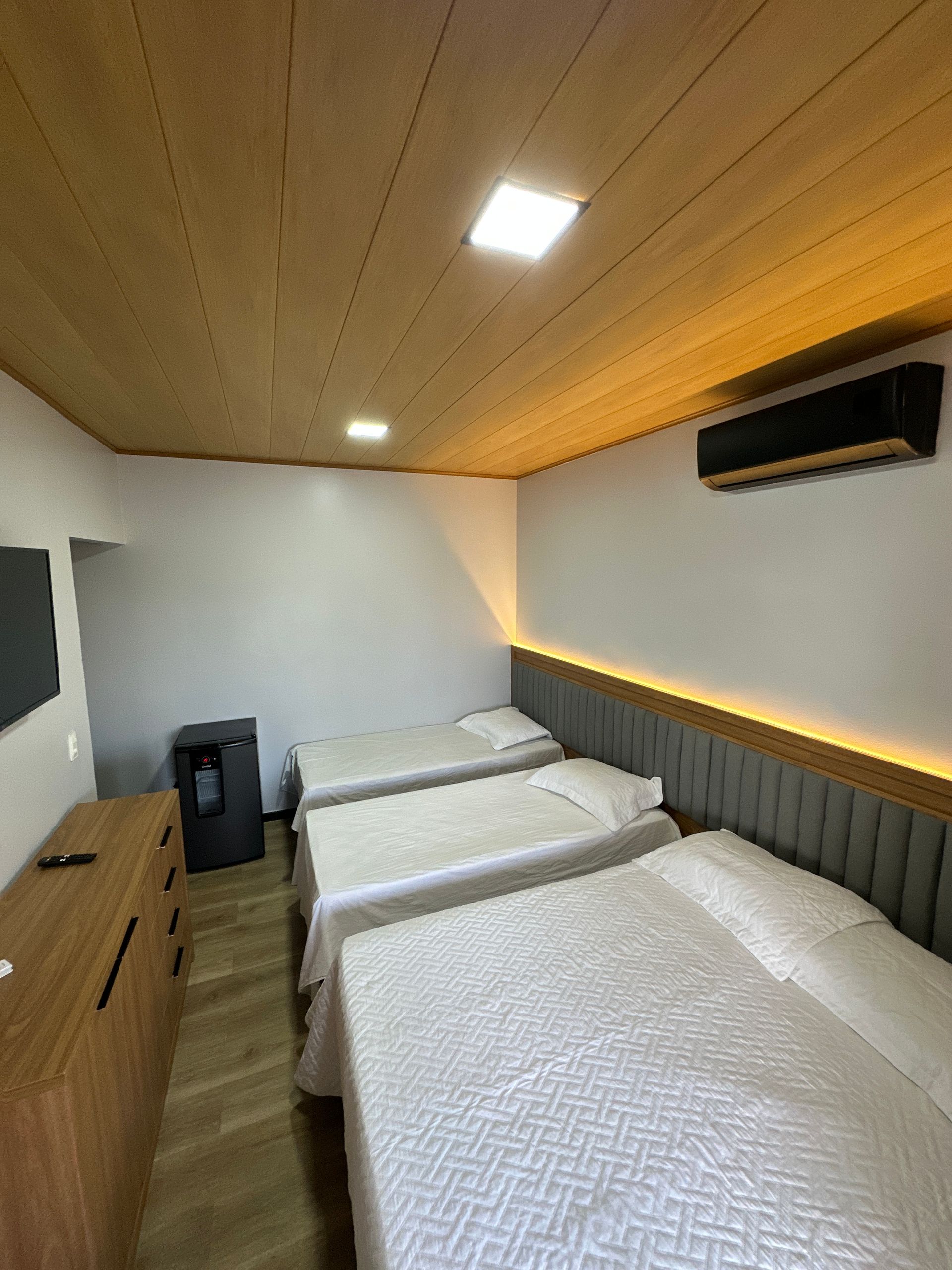 Um quarto de hotel com três camas e uma televisão.