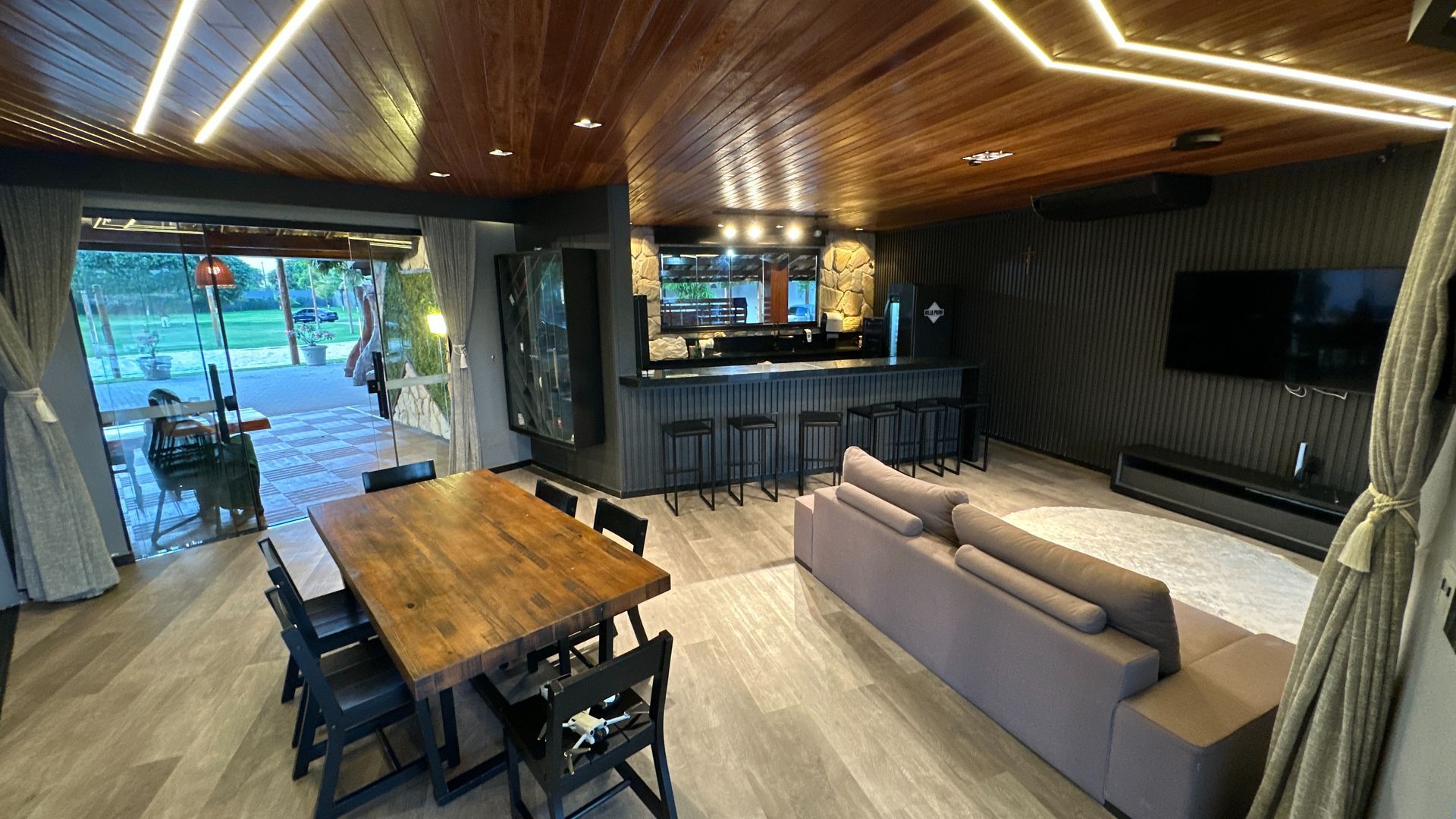 Uma sala de estar com um sofá, mesa, cadeiras e uma televisão.