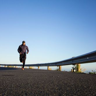 a man running down a road with a blue sky in the background