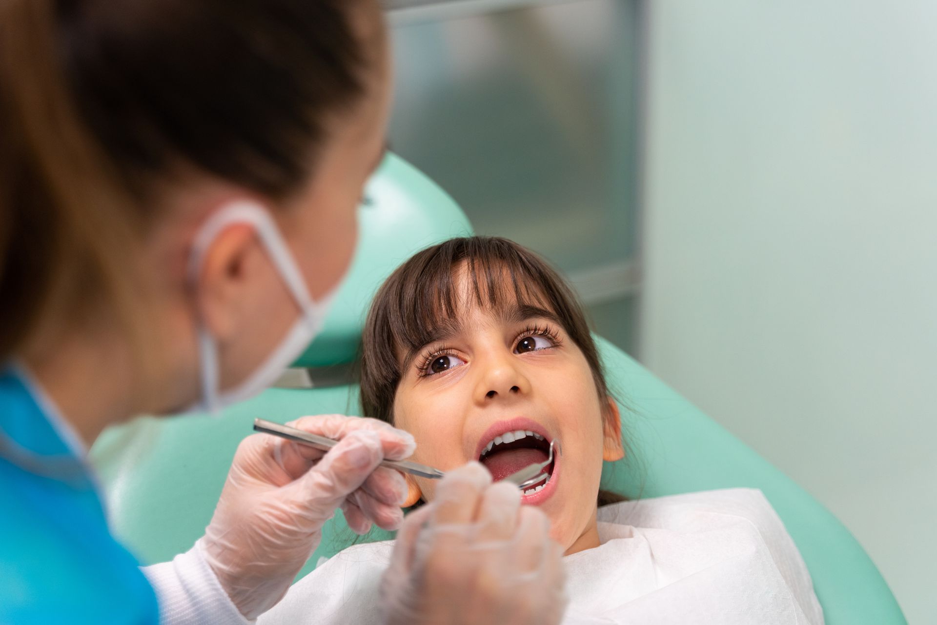The dentist is examining the girl's teeth. The dentist is examining the girl's teeth.