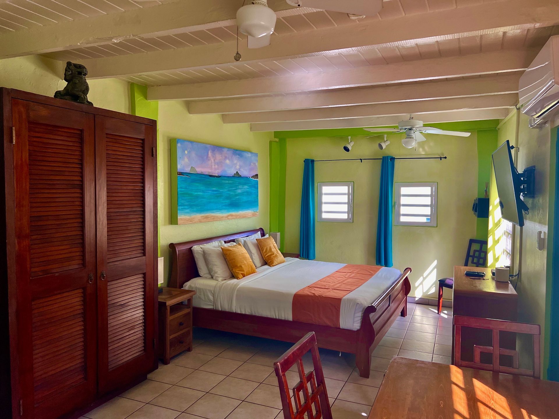 Bedroom with a bed, wooden wardrobe, painting, and teal accents; lime green walls and white beams.