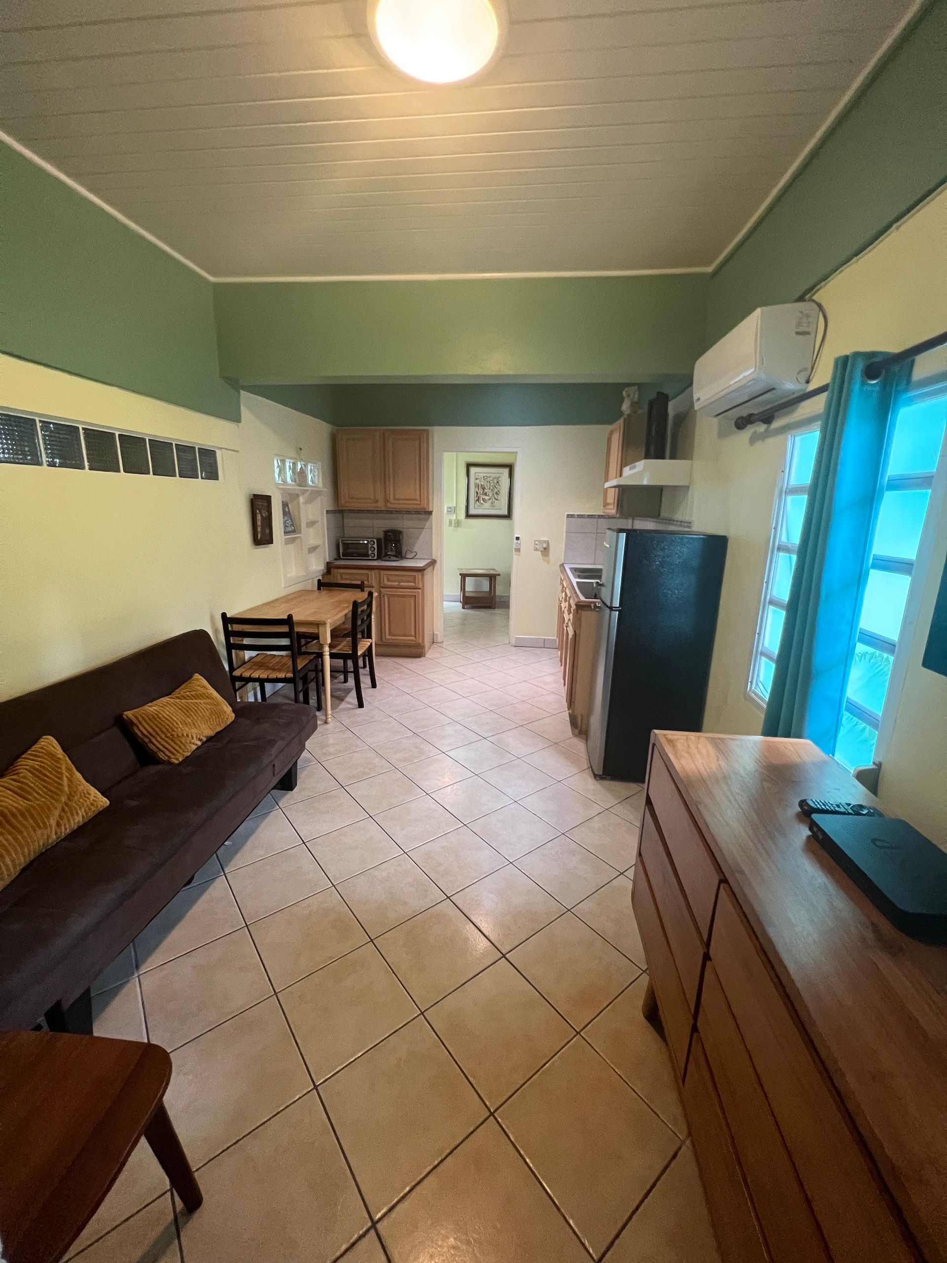Small apartment with a living area, kitchen, and dining area. Beige tiled floor.