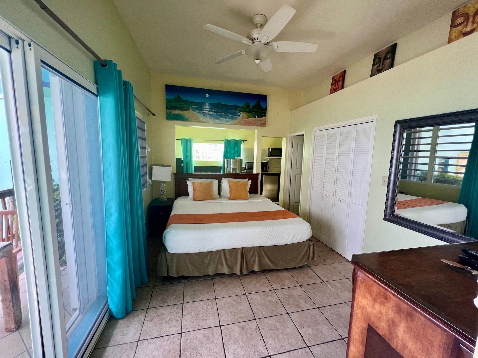 Bedroom with king bed, turquoise curtains, and ocean view.