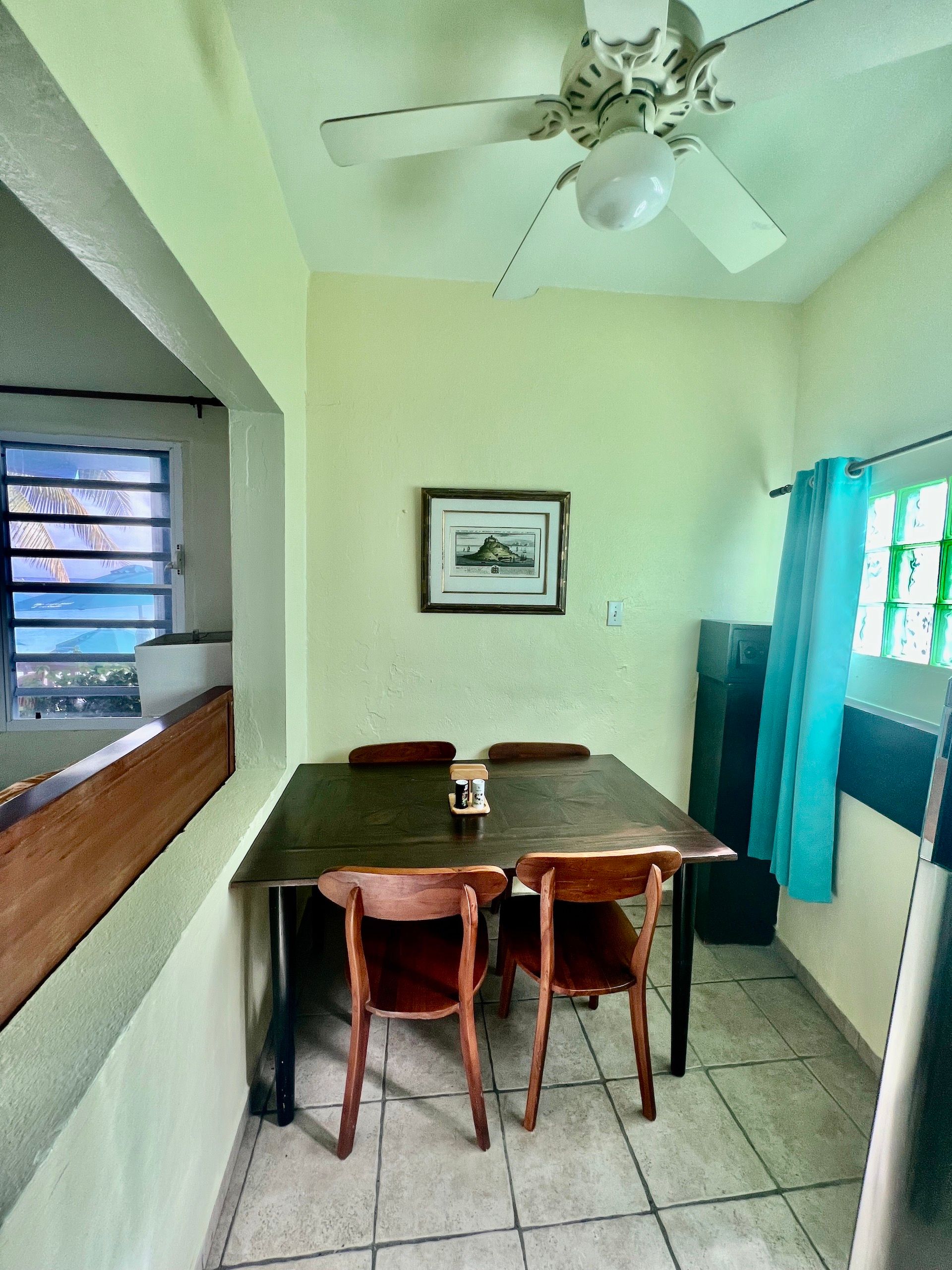 Small dining room with table, chairs, art, window, and ceiling fan.