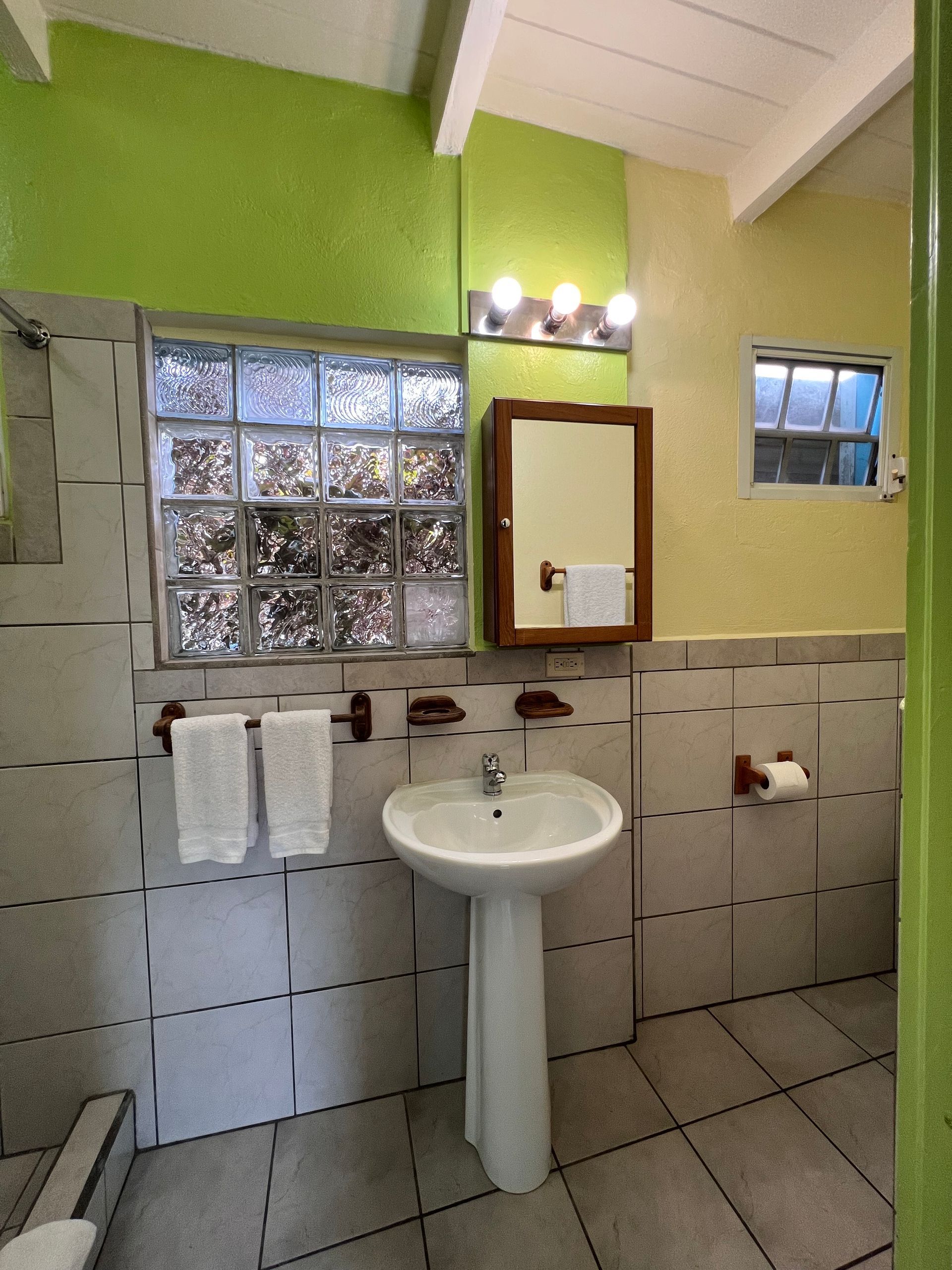 Bathroom with pedestal sink, tile walls, glass block window, and lime green walls.