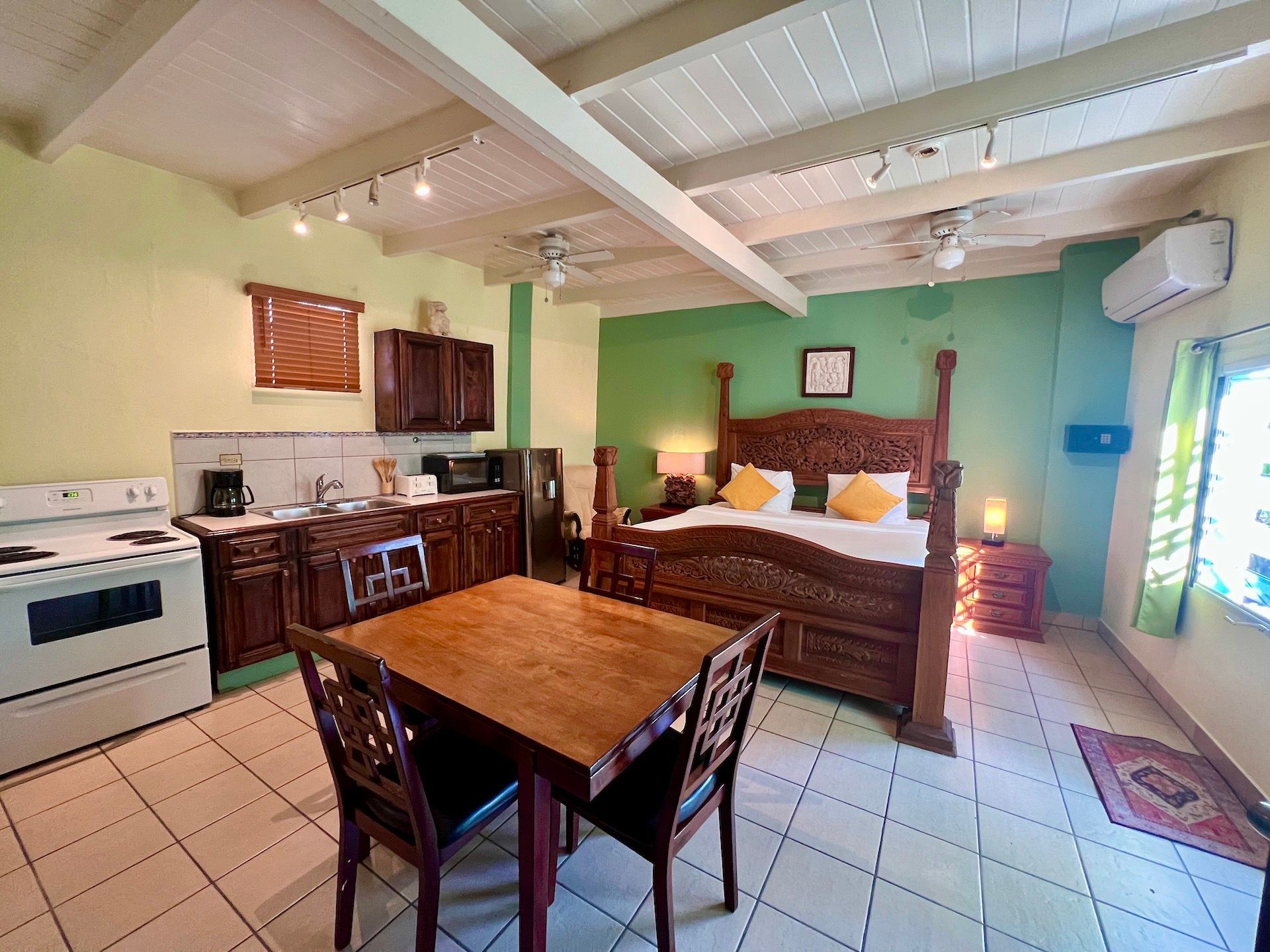 Studio apartment with a wooden bed, kitchen, and dining table.