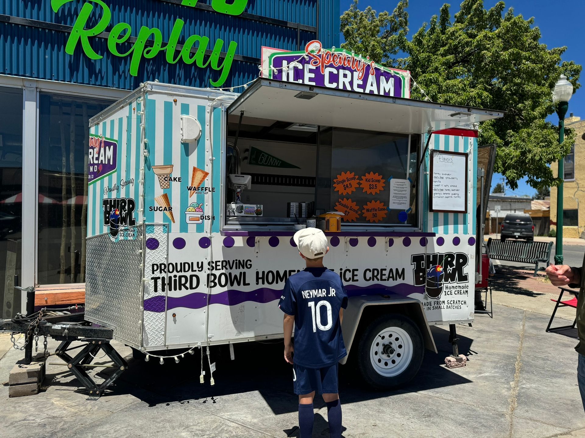 A boy is standing in front of an ice cream truck.