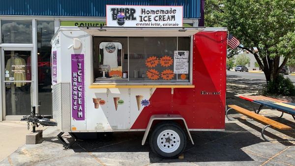 a homemade ice cream trailer is parked in front of a store