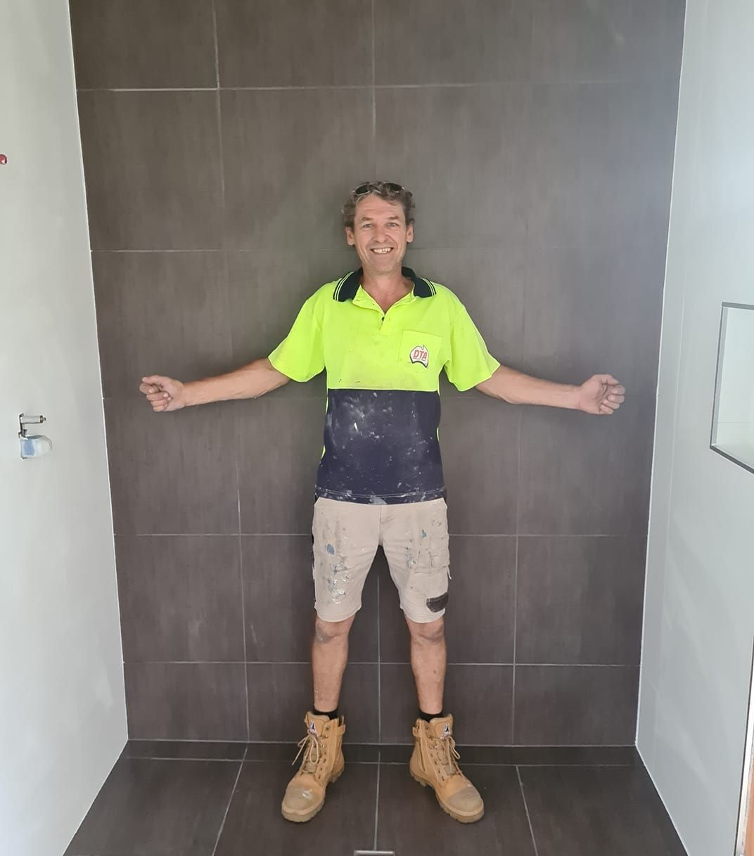 Man in Work Clothes Stands in Front of Tiled Wall — Tropic Tiling in Tolga, QLD