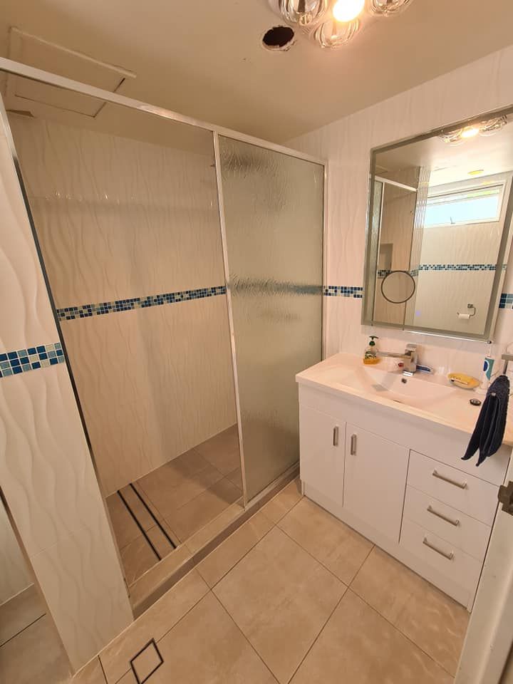 Bathroom With a Shower, Vanity, Mirror, and White and Blue Tile Accents — Tropic Tiling in Yungaburra, QLD