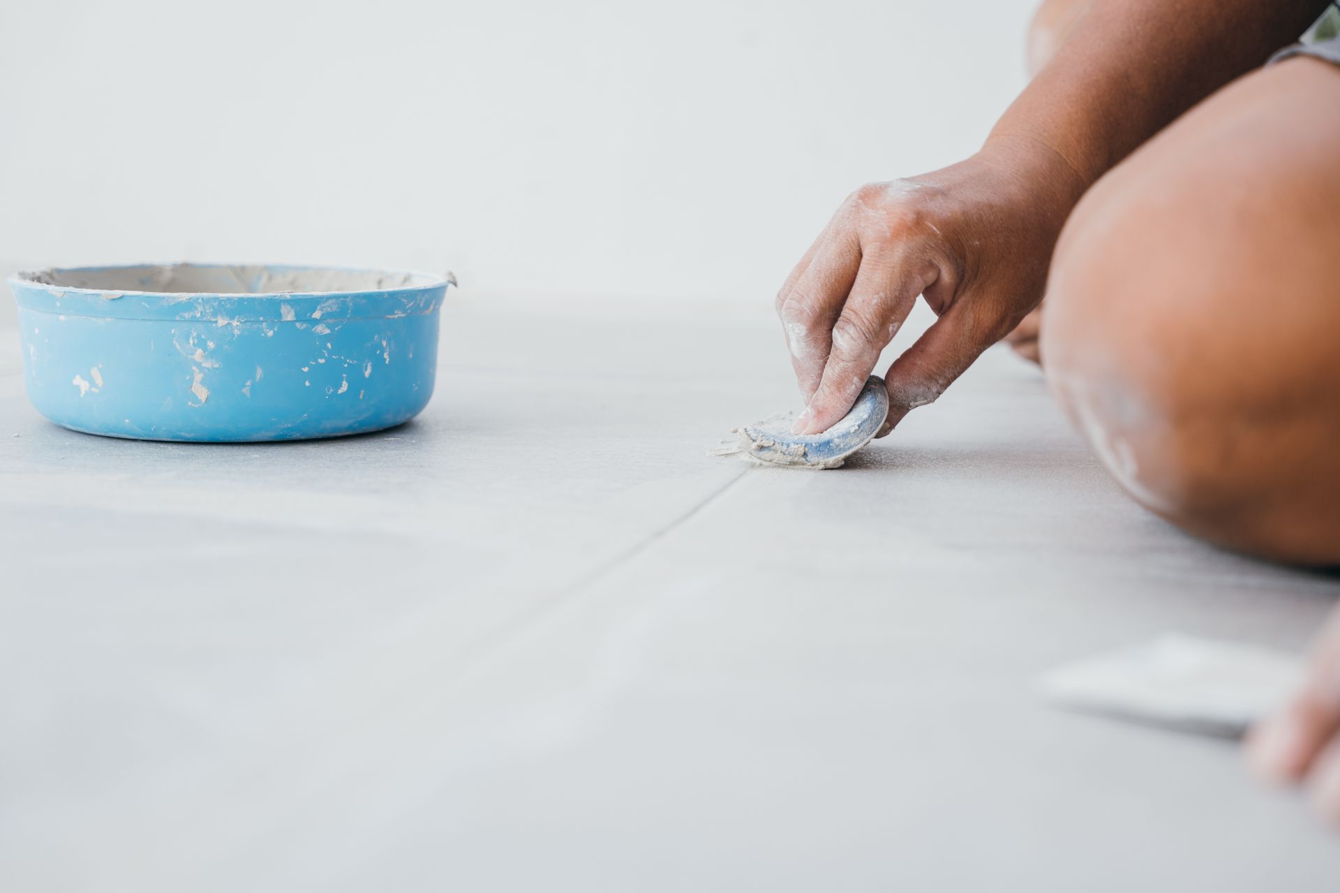 Person on Floor Applying Putty to a Crack With a Tool — Tropic Tiling in Malanda, QLD