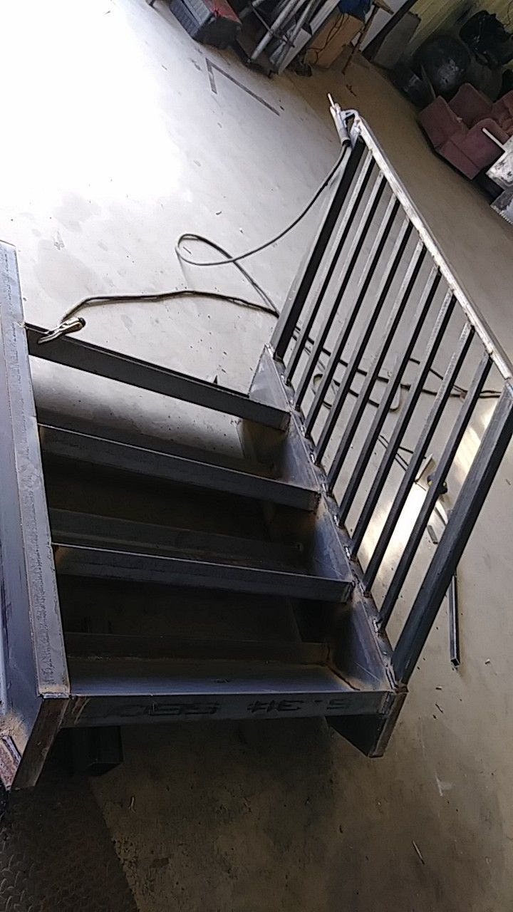 A metal staircase with a railing is sitting on the floor in a garage.
