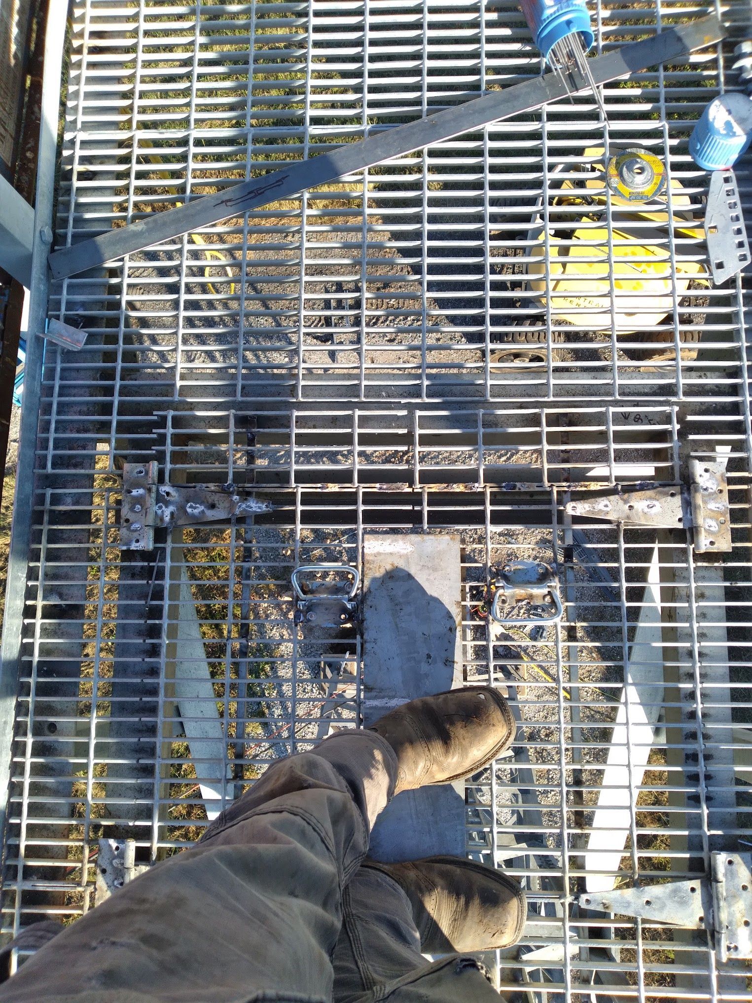 A person is standing on a metal grate with a saw.