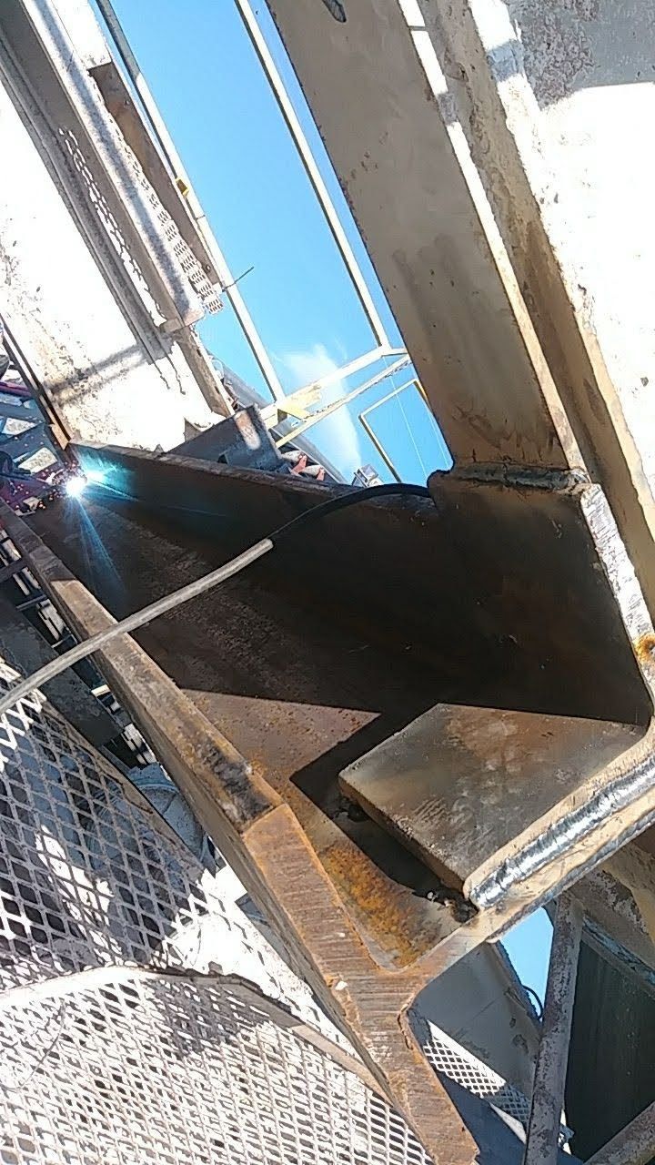 A person is welding a piece of metal on a bridge.