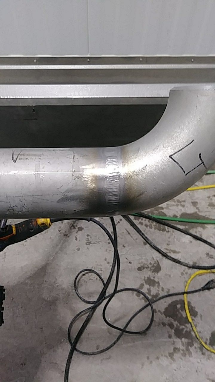 A stainless steel pipe is being welding in a garage.