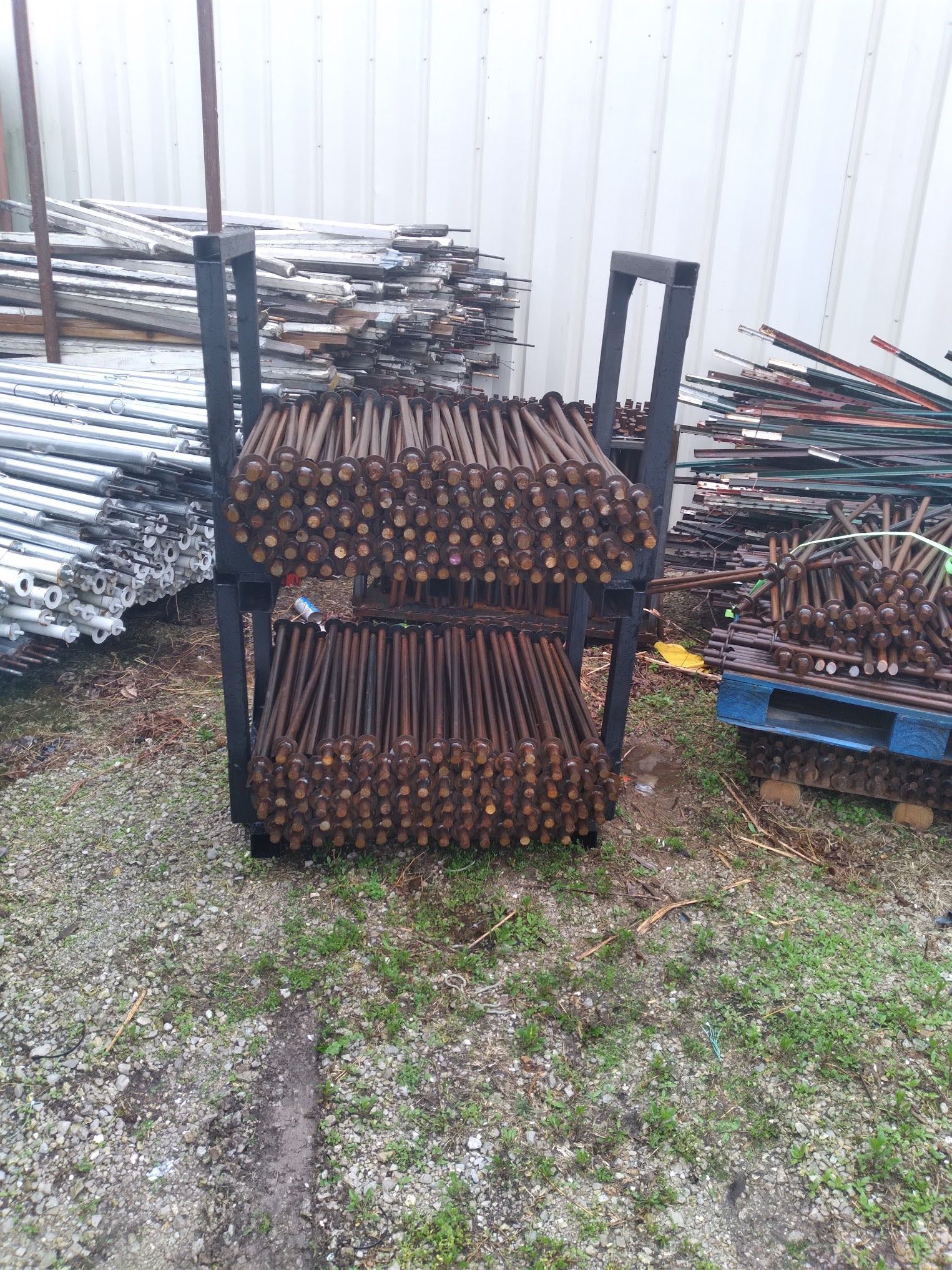 A bunch of scaffolding poles are stacked on top of each other in a yard.