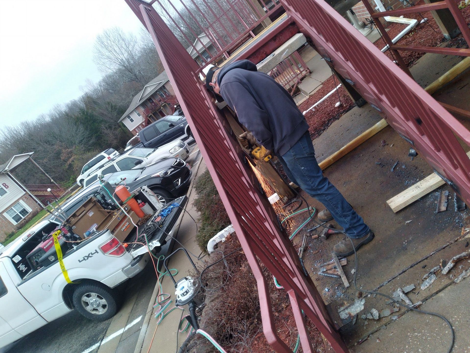 A man is working on a metal structure in a parking lot.