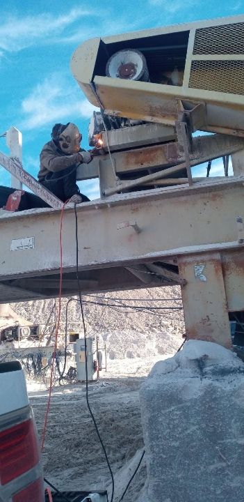 A man is welding a machine on top of a bridge.