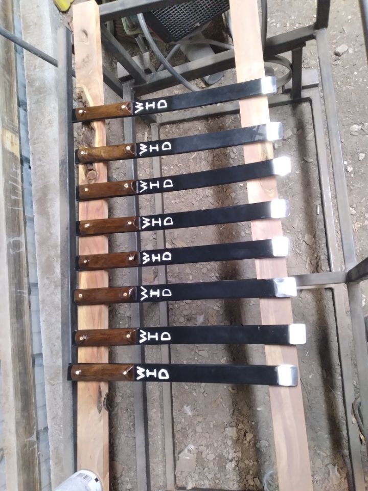 A bunch of knives are lined up on a wooden shelf