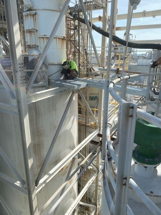 A man is working on a large metal structure in a factory.