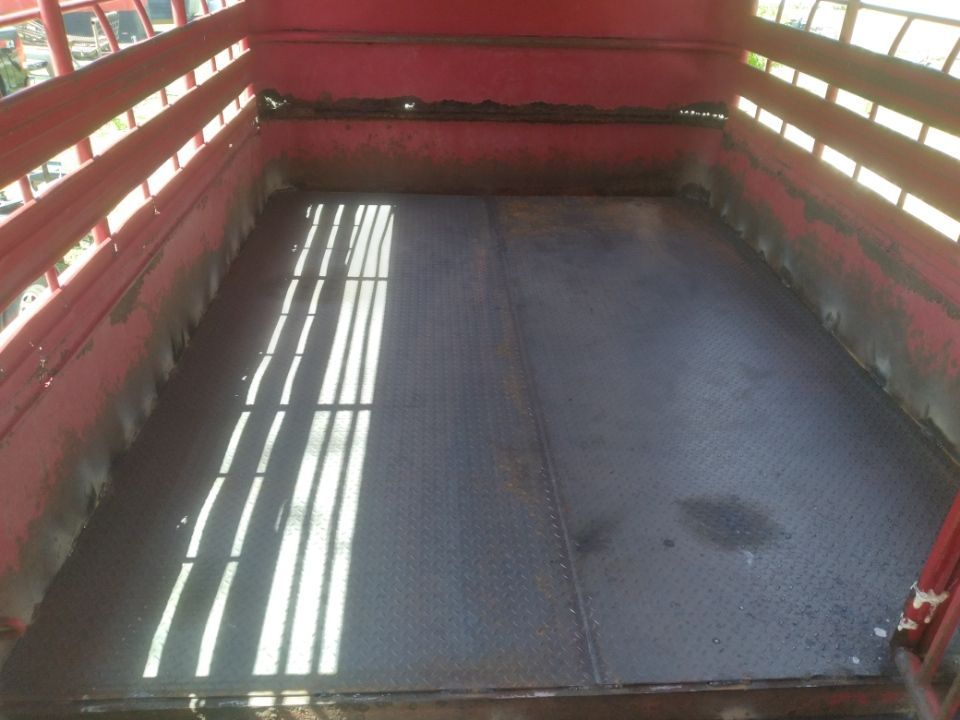The inside of a red trailer with a metal floor