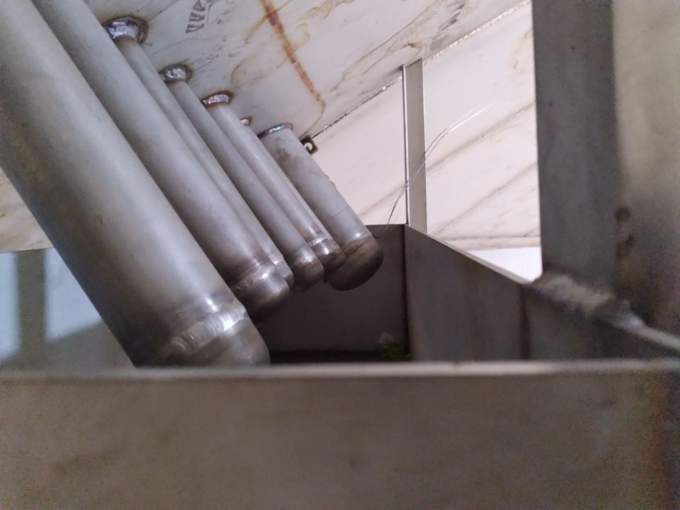 A row of stainless steel pipes are lined up in a row