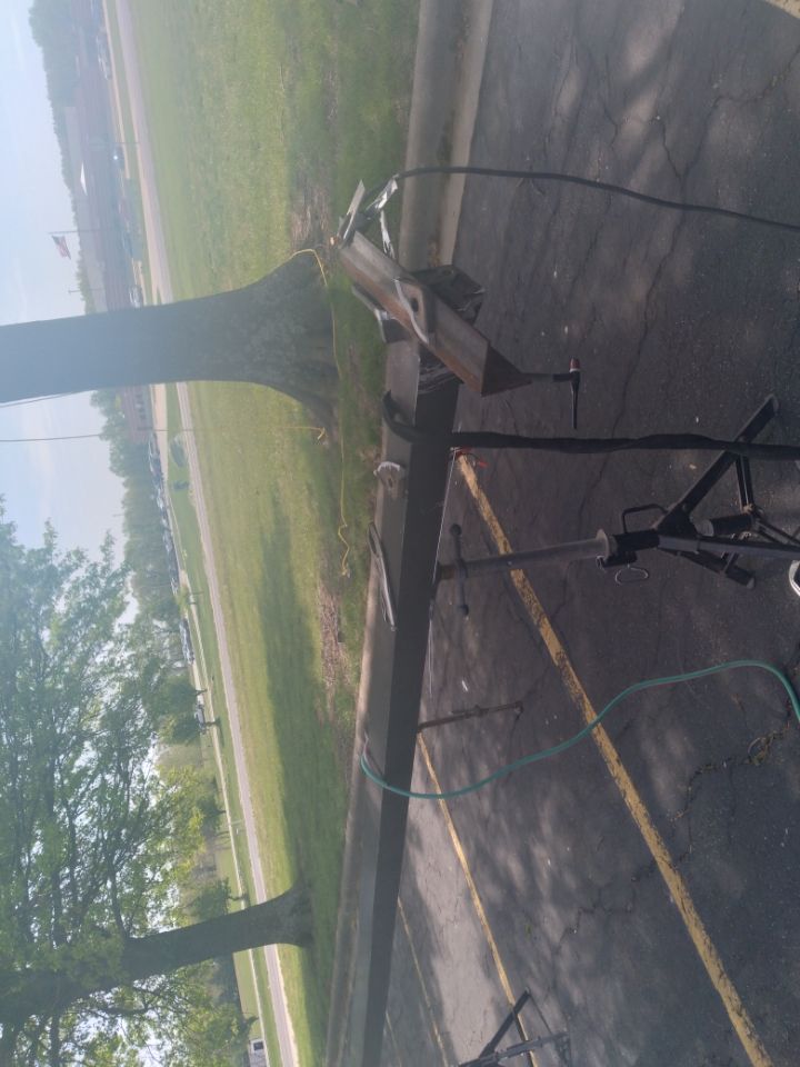 A trailer is parked on the side of the road next to a tree.