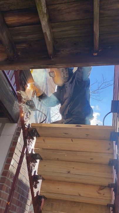 A man is cutting a piece of wood on a porch.