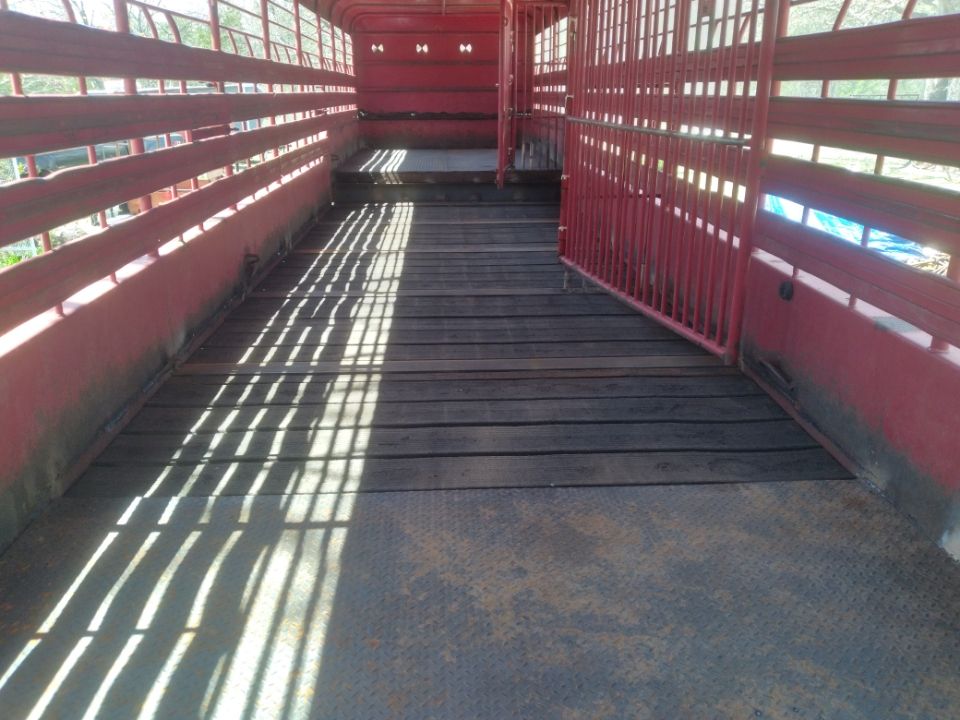 The inside of a red cattle trailer with a wooden floor