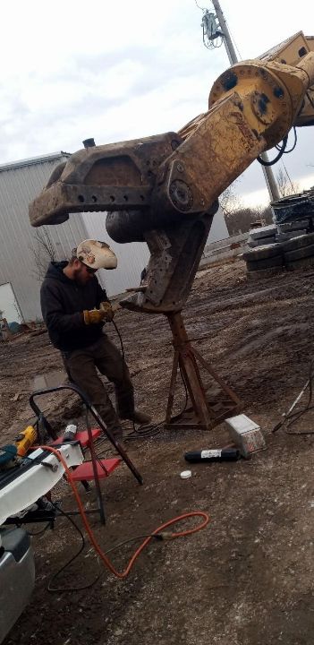 A man is working on a piece of equipment in a dirt field.