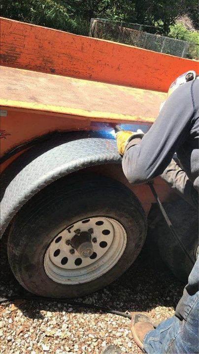 A man is standing next to an orange trailer.