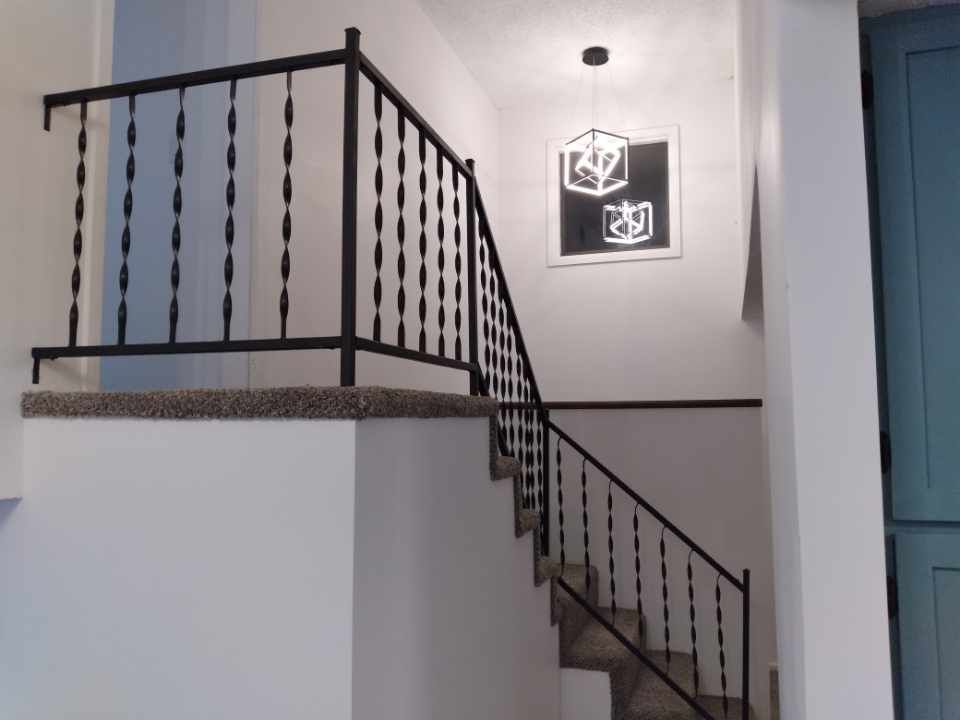 A staircase with a wrought iron railing and a picture on the wall.