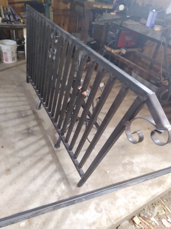 A wrought iron railing is sitting on the ground in a garage.