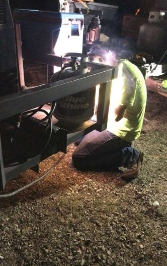 A man is kneeling down in front of a welding machine.