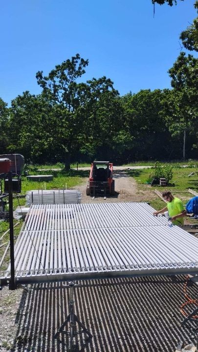 A man is working on a concrete driveway with a tractor in the background.