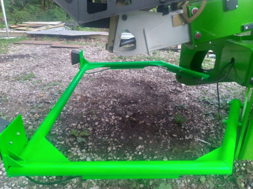A green frame is sitting on the ground next to a green vehicle.