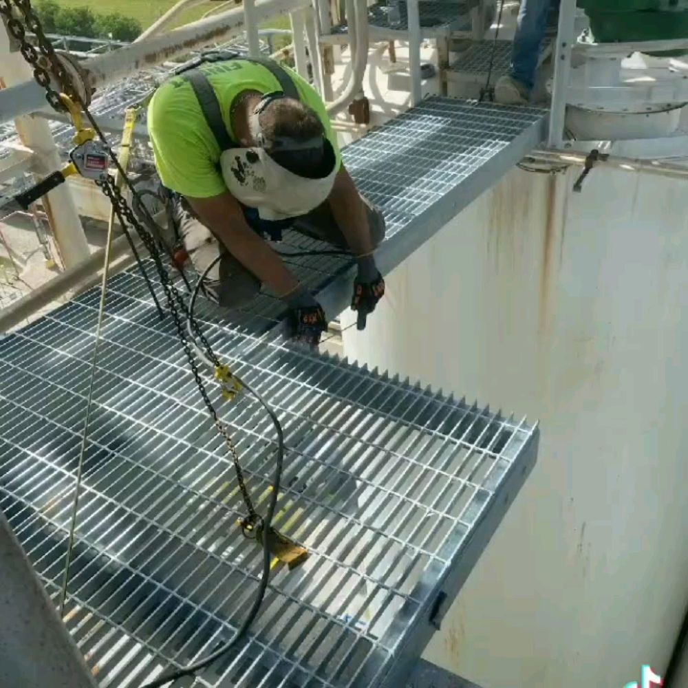 A man is working on a metal platform on top of a building.