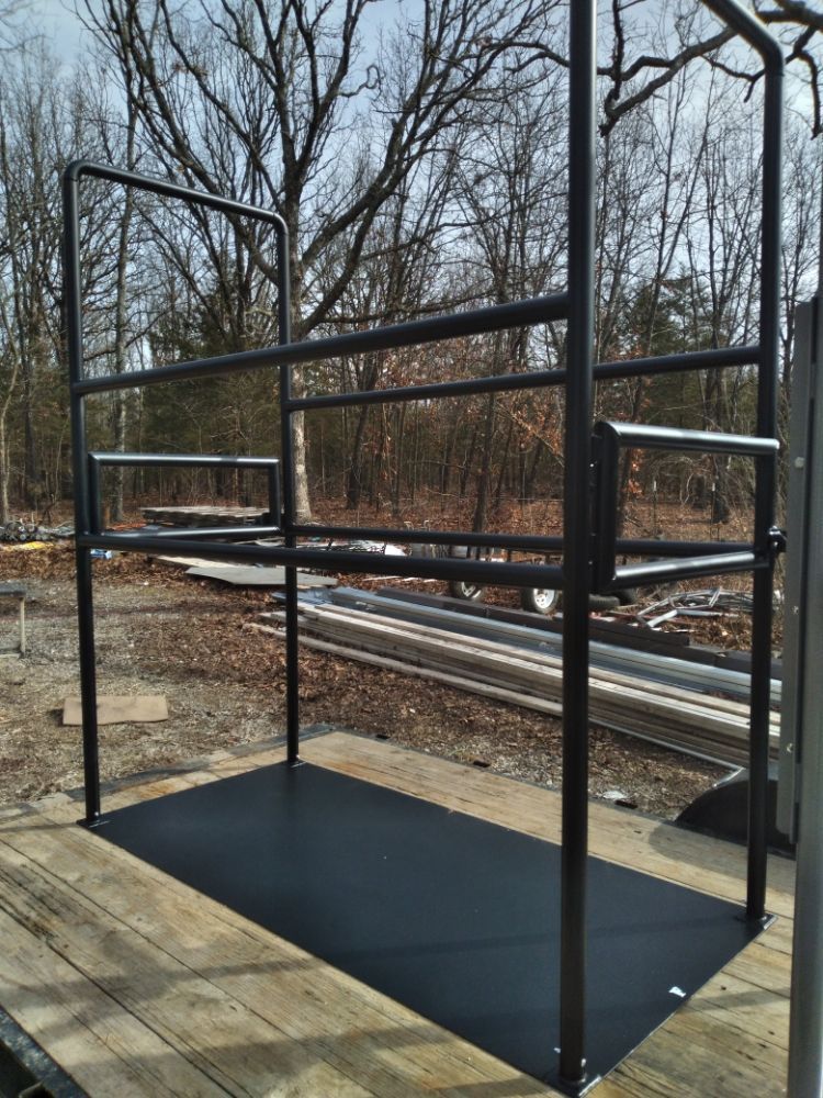 A black metal structure is sitting on a wooden deck with trees in the background.