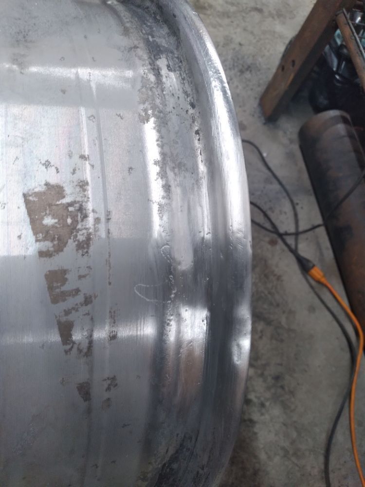 A close up of a dirty aluminum wheel in a garage.