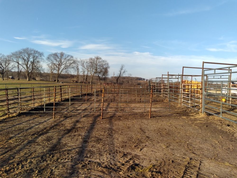 There is a fence in the middle of a dirt field.