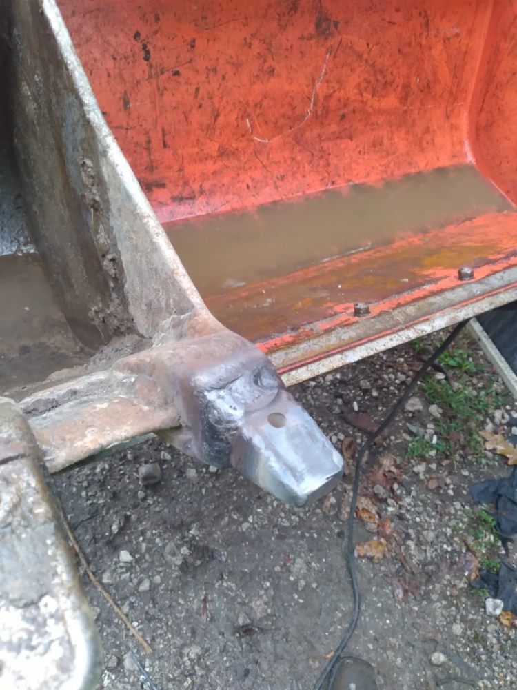 A piece of metal is sitting on the ground next to a bucket.