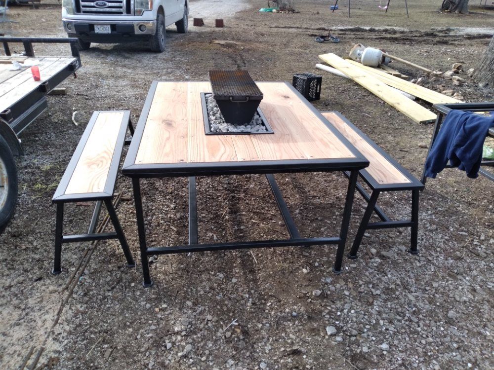 A picnic table with two benches and a fire pit in the middle