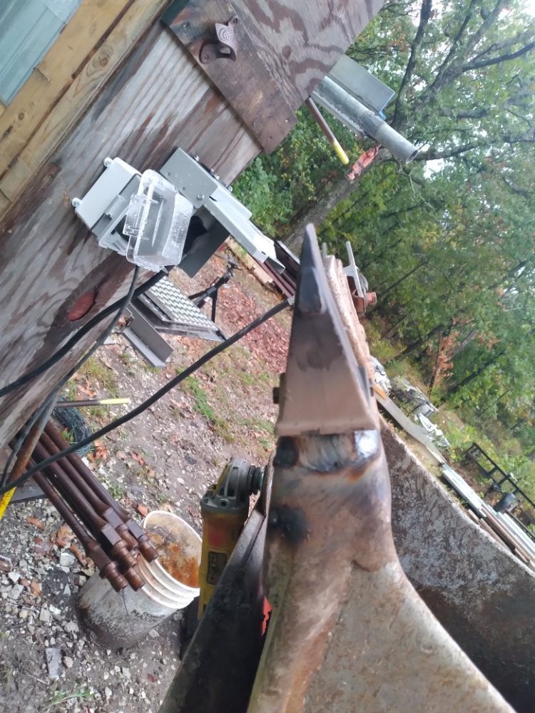 A blacksmith 's anvil is sitting in front of a wooden building.