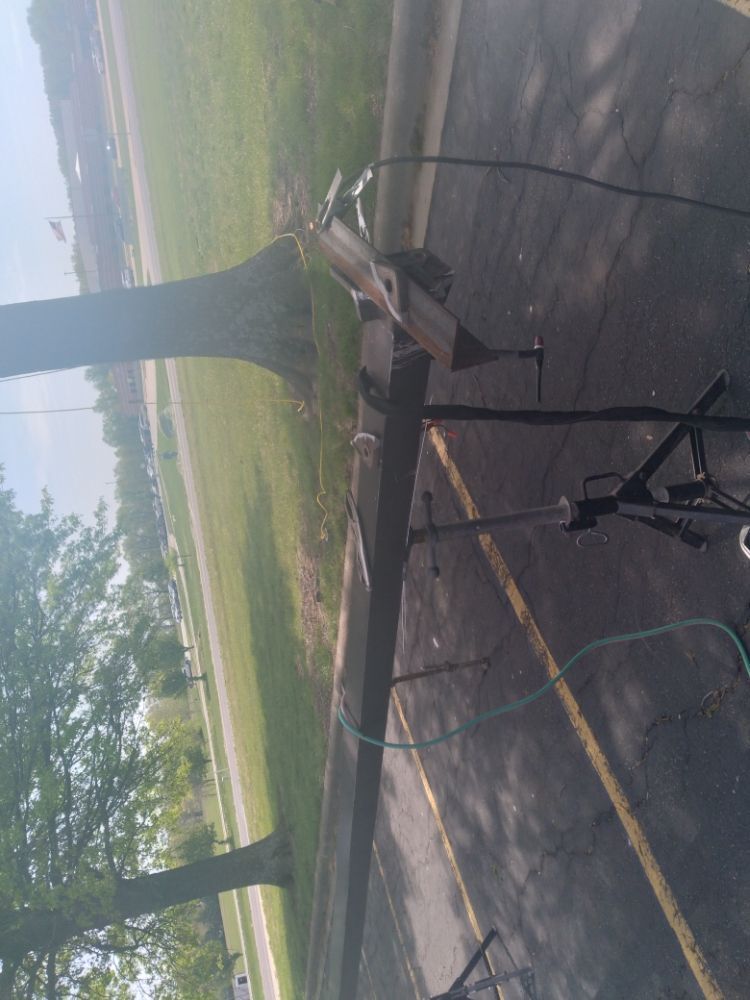 A trailer is parked on the side of the road next to a tree.