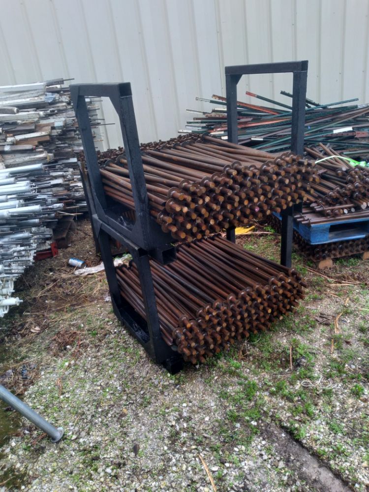 A bunch of metal bars are stacked on top of each other on the ground.