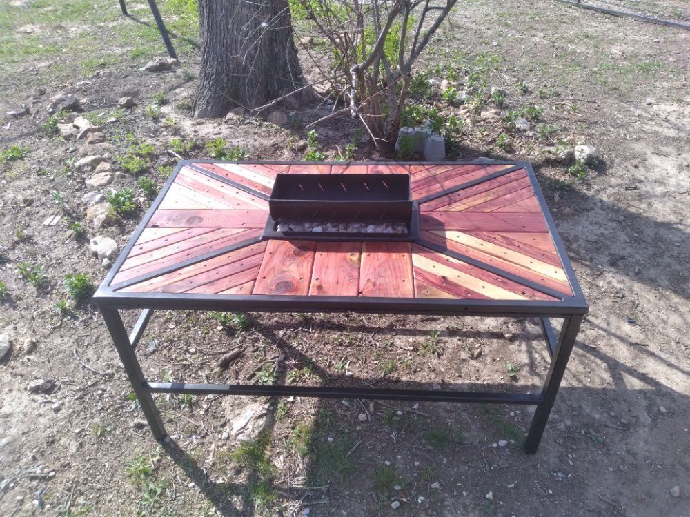 A wooden table with a metal frame and a grill on top of it.