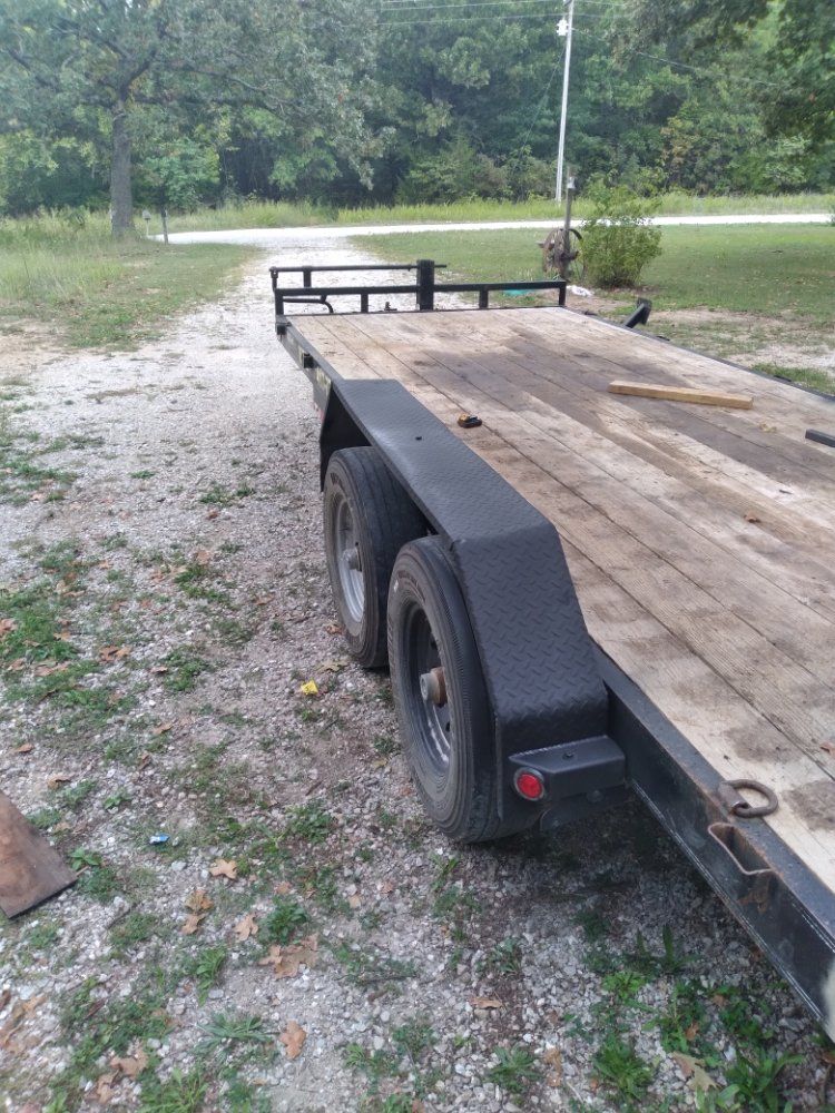 A flatbed trailer is parked on the side of a dirt road.