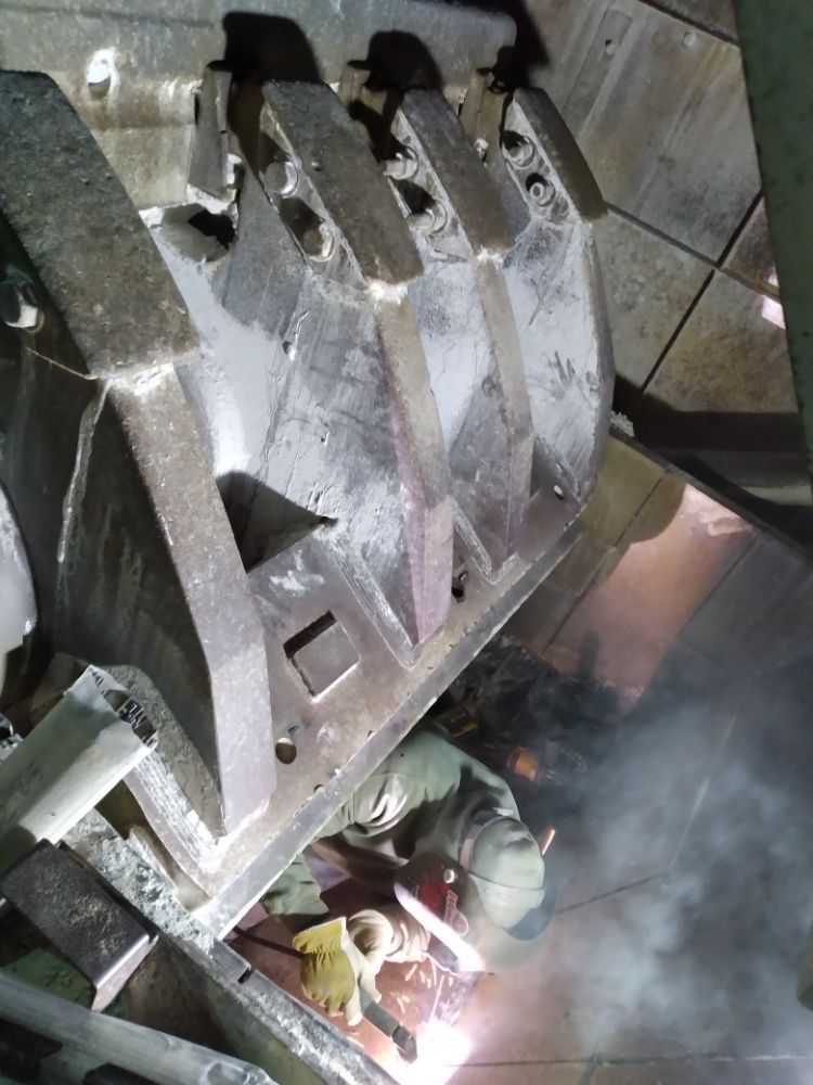 A man is welding a piece of metal in a factory.