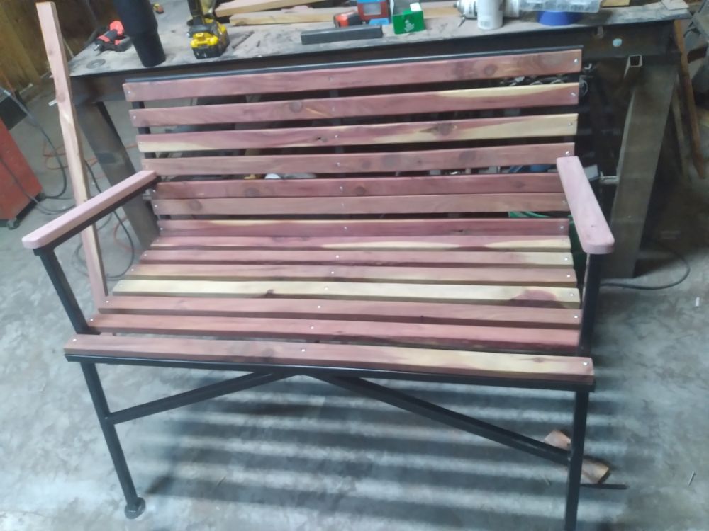 A wooden bench is sitting on a concrete floor in a workshop.