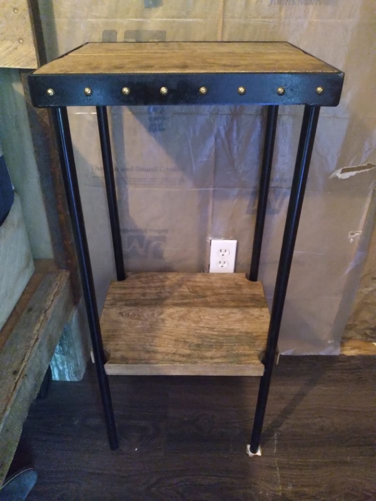 A small table with a wooden top and metal legs is sitting on a wooden floor.